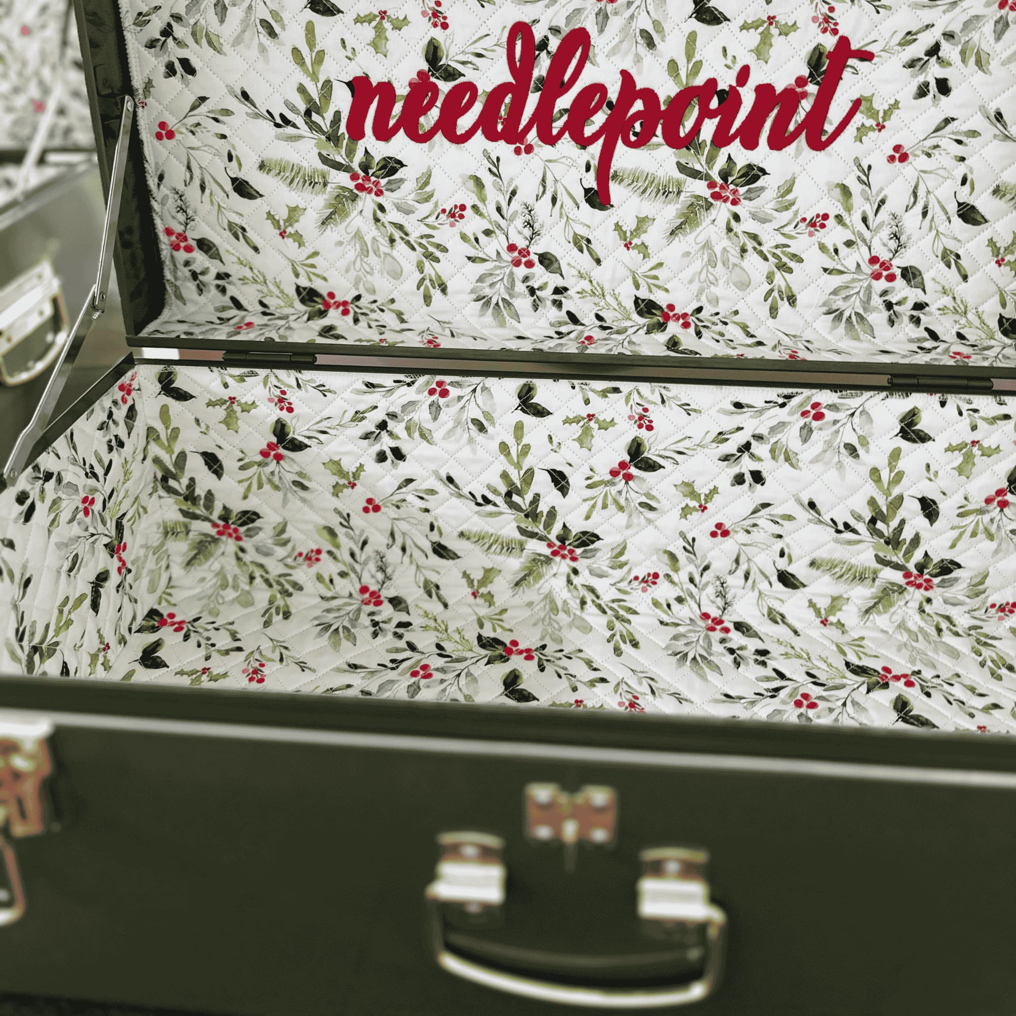 green memory box with branches and boughes on the fabric and 'needlepoint' text on a white background