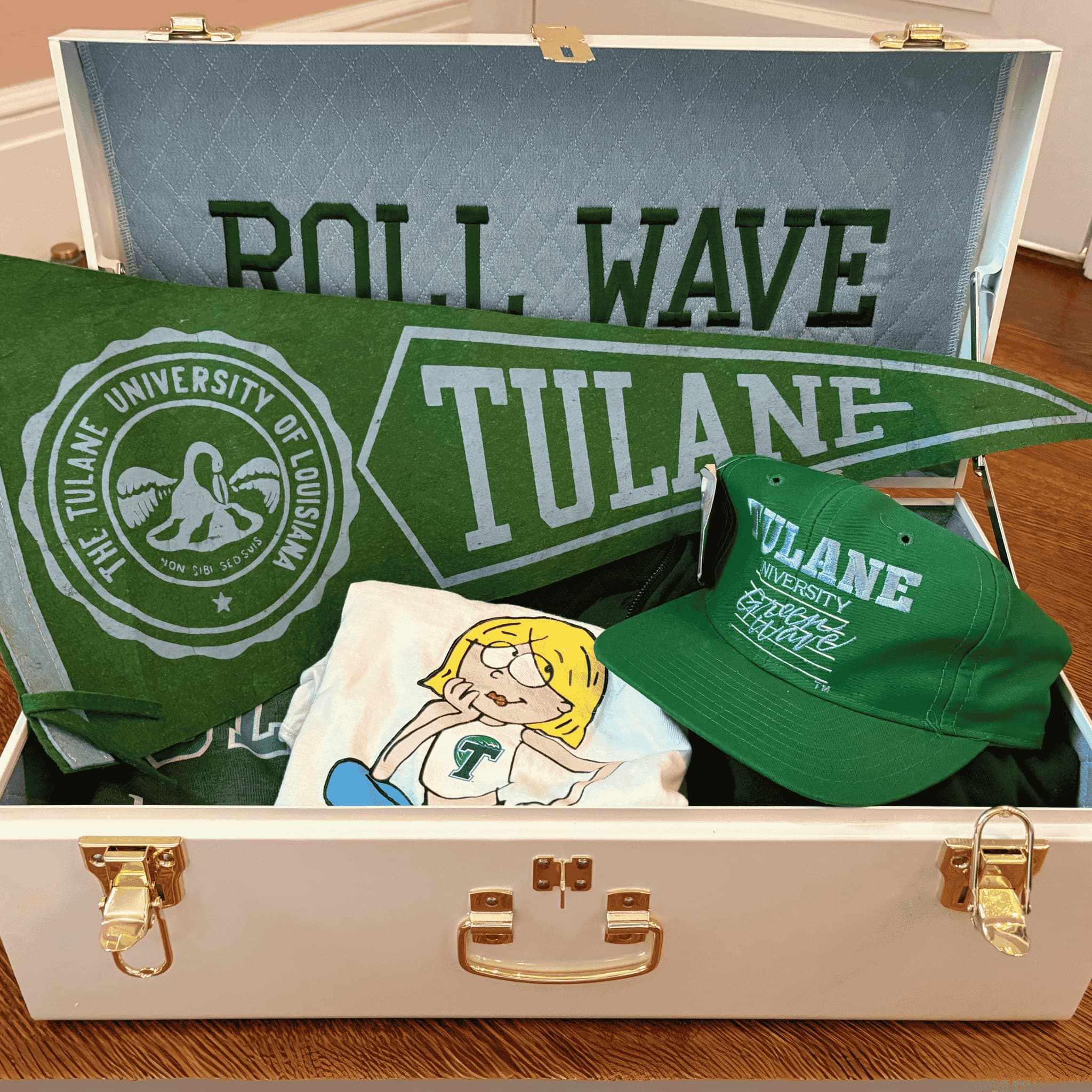 Collection of college merchandise including a cap, towel, and pillow in an keepsake trunk.