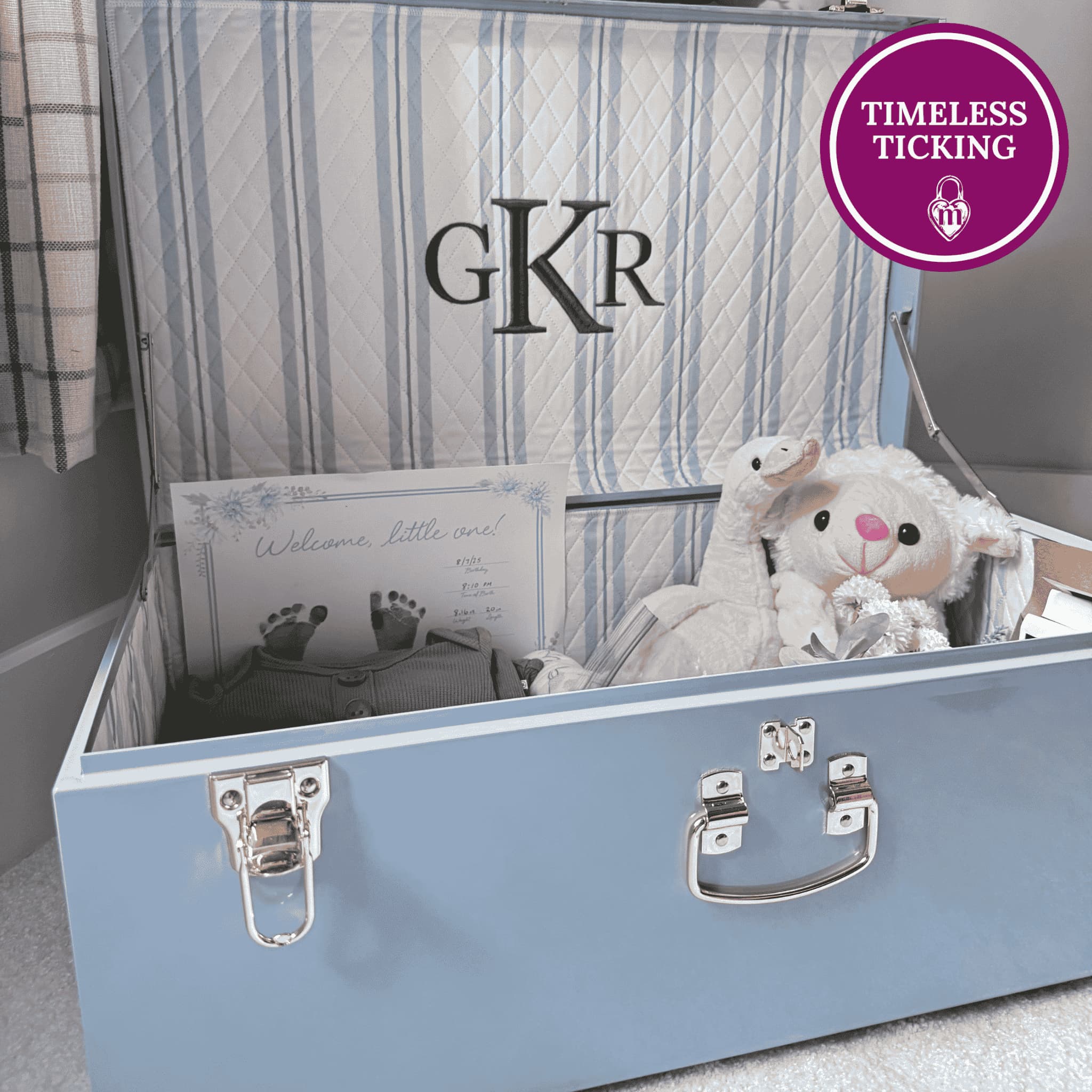 Blue baby trunk with baby items and 'GKR' branding, featuring a lamb plush toy.