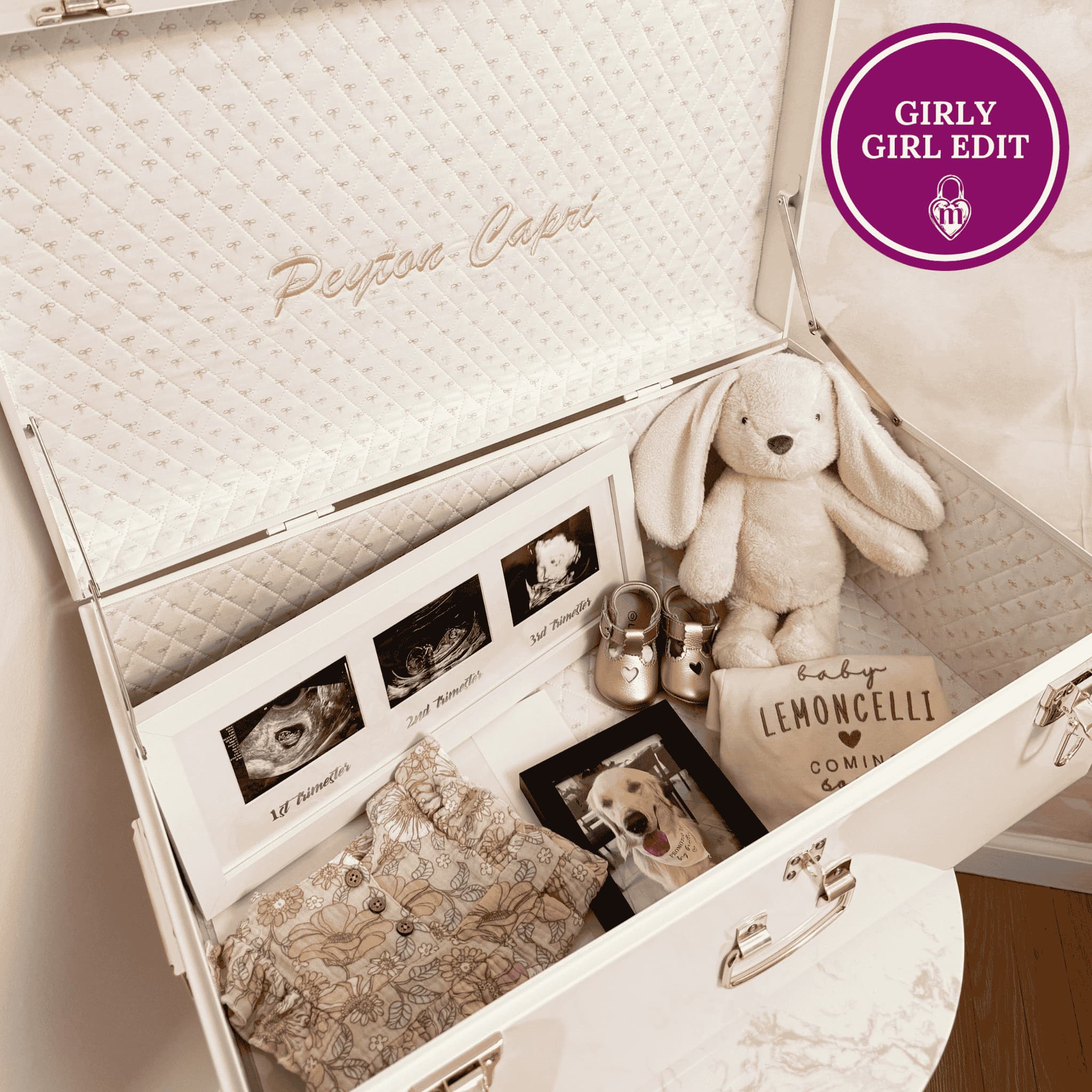 Open baby gift box with plush toy, photo album, and baby shoes on a wooden surface.