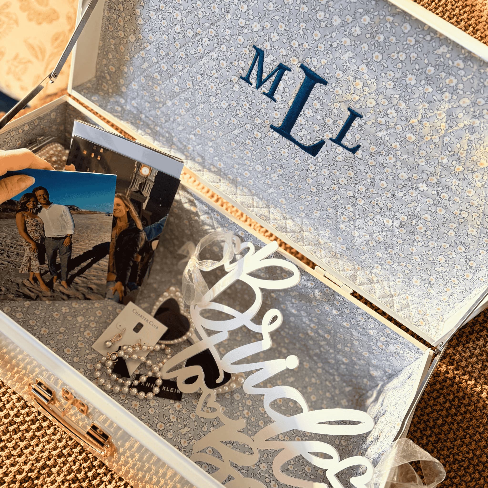 Open jewelry box with 'MILL' initials, photos, and jewelry inside.