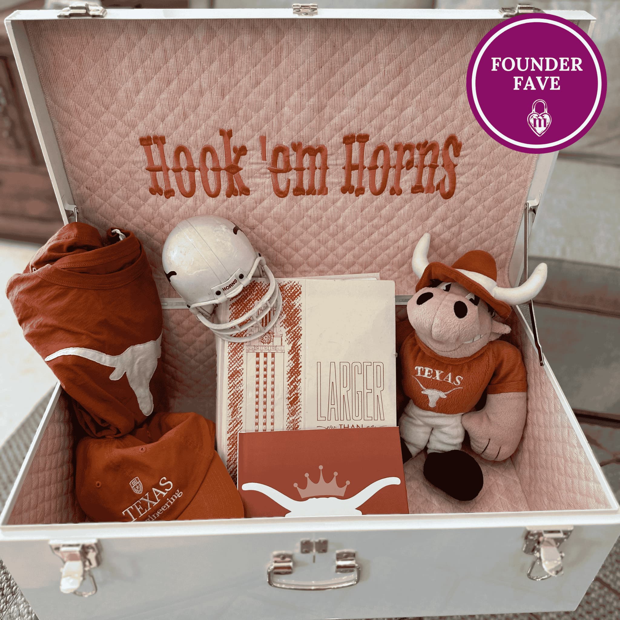 Open memory box with college text, Texas-themed items, and a plush cow toy.