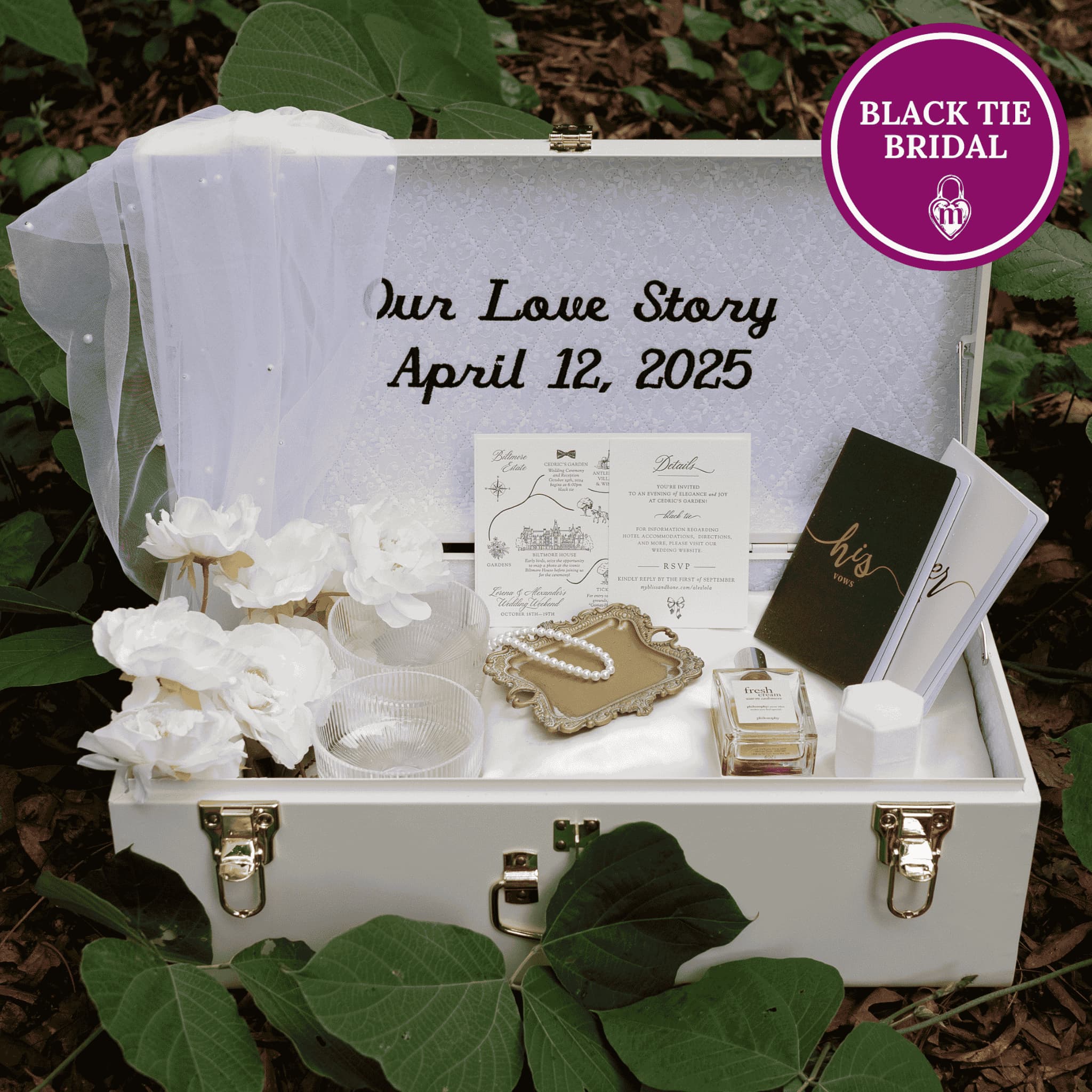White wedding-themed box with 'Our Love Story April 12, 2025' text, surrounded by green leaves.